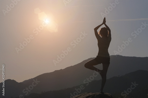 Woman practicing yoga, mountains and sky background