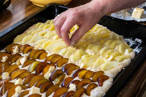 Obstkuchen mit Hefeteig auf Backblech mit Pflaumen und Äpfel im Backofen frisch gebacken.