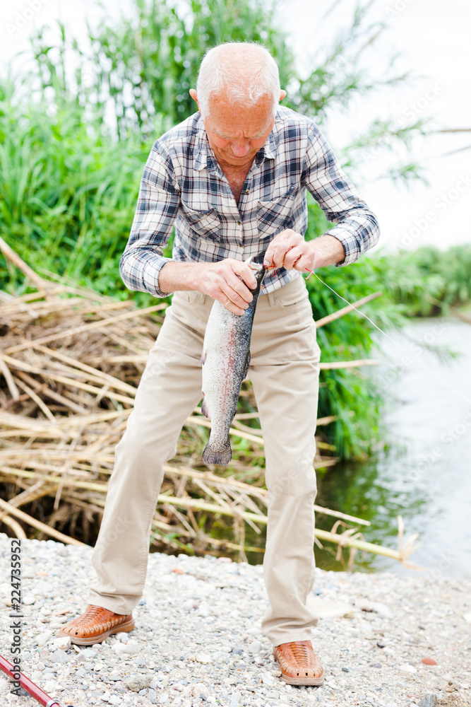 Fototapeta premium Fisherman pulling fish from river