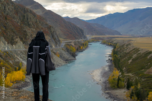 Фотография tourist, a man in a sports jacket on the mountain looks at the autumn mountain l