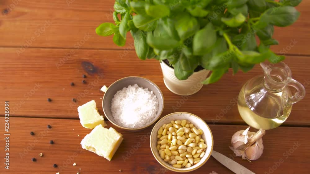 food and culinary concept - parmesan cheese, pine nuts, sea salt and garlic for basil pesto sauce making on wooden table food and culinary concept - parmesan cheese, pine nuts, sea salt and garlic for basil pesto sauce making on wooden table