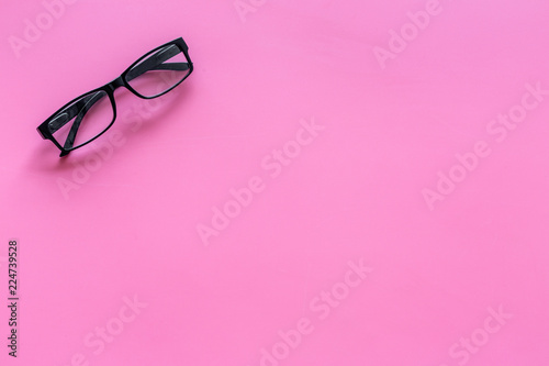 Glasses with transparent optical lenses on pink background top view space for text