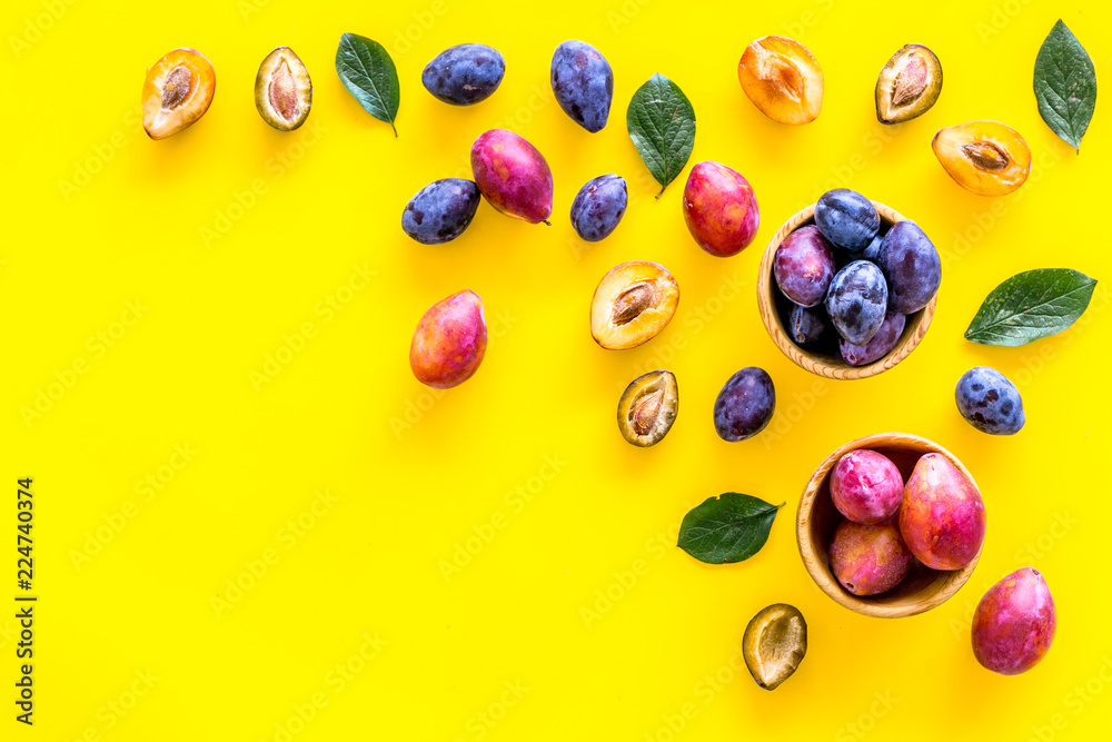Bright fruitty background. Plum pattern. Red and purple plum and leaves on yellow background top view copy space Bright fruitty background. Plum pattern. Red and purple plum and leaves on yellow background top view copy space