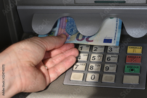 Mano di persona fuori campo preleva biglietti da 20 euro da uno sportello automatico