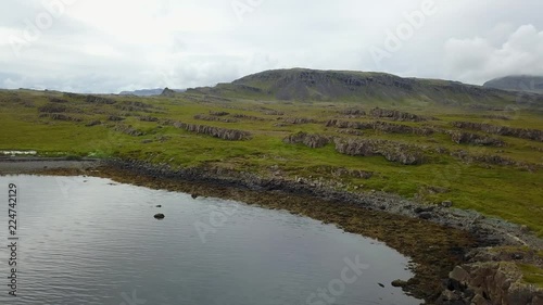 Eastern Icelandic drone shot of small rock pile and lighthouse near coast