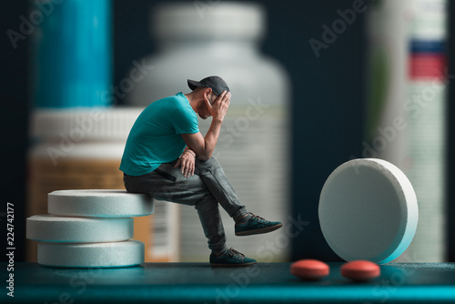 The man sitting on the pills. He's depressed. Flacons of medicines in the background