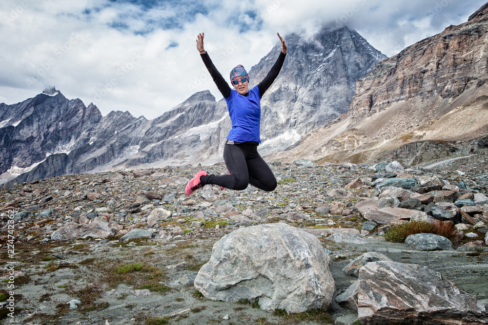 Woman jumping from a rock in the Italian mountainous alps