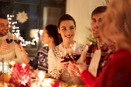 winter holidays and people concept - happy friends celebrating christmas at home feast and drinking red wine