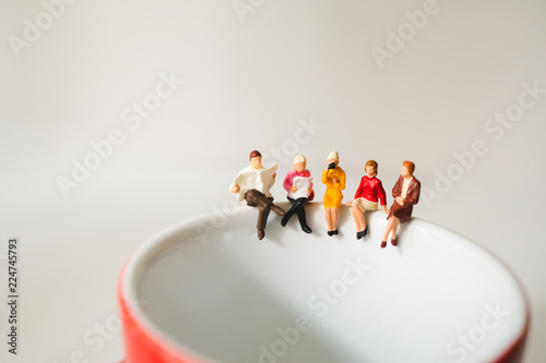 Miniature people  sitting on cup of coffee using as business meeting and social concept