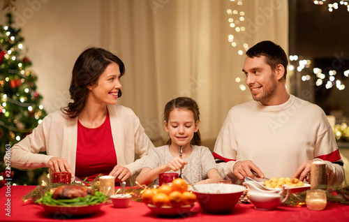 holidays  family and celebration concept - happy mother  father and little daughter having christmas dinner at home