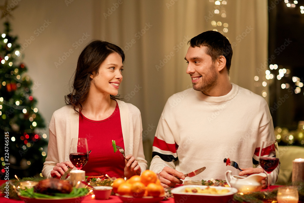 holidays, eating and celebration concept - happy couple having christmas dinner at home