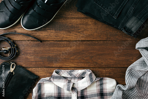 Women's clothing and accessories on a wooden background, black shoes, bag, jeans and shirt, hipster style