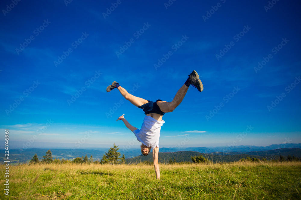 Young happy guy having fun on top of hill, the mountains on background Young happy guy having fun on top of hill, the mountains on background