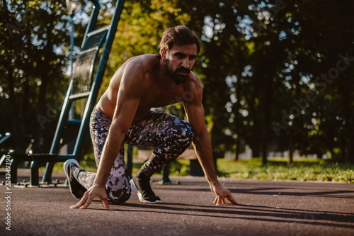 Athletic bearded man in running start position at the outdoor gym © sasamihajlovic