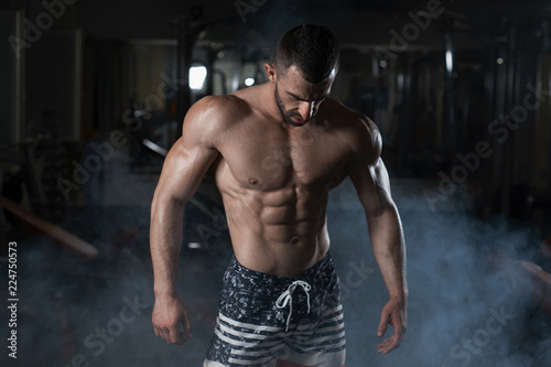 Strong fitness man shows his athletic body in the gym. The concept of a healthy lifestyle