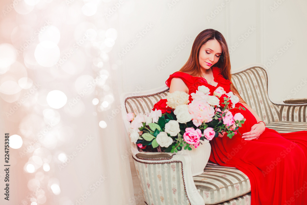 Beautiful pregnant woman touching her belly with hands in the living room having, the light give a cozy atmosphere. Beautiful pregnant woman touching her belly with hands in the living room having, the light give a cozy atmosphere.
