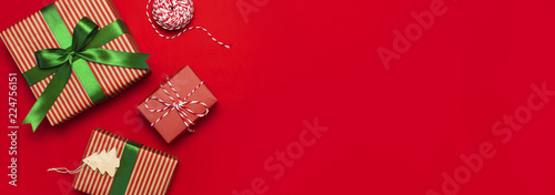 Gift boxes with green ribbon on red background top view flat lay. Holiday concept, new year or Christmas gift box, presents Xmas holiday. Congratulations background with space for text long banner