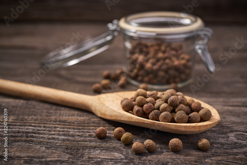 Dried allspice in a wooden spoon close-up photo