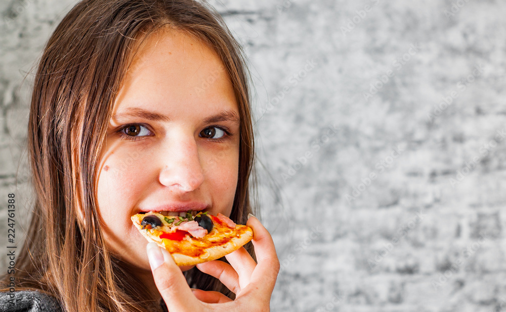 portrait of young teenager brunette girl with long hair eating slice of pizza on gray wall background portrait of young teenager brunette girl with long hair eating slice of pizza on gray wall background