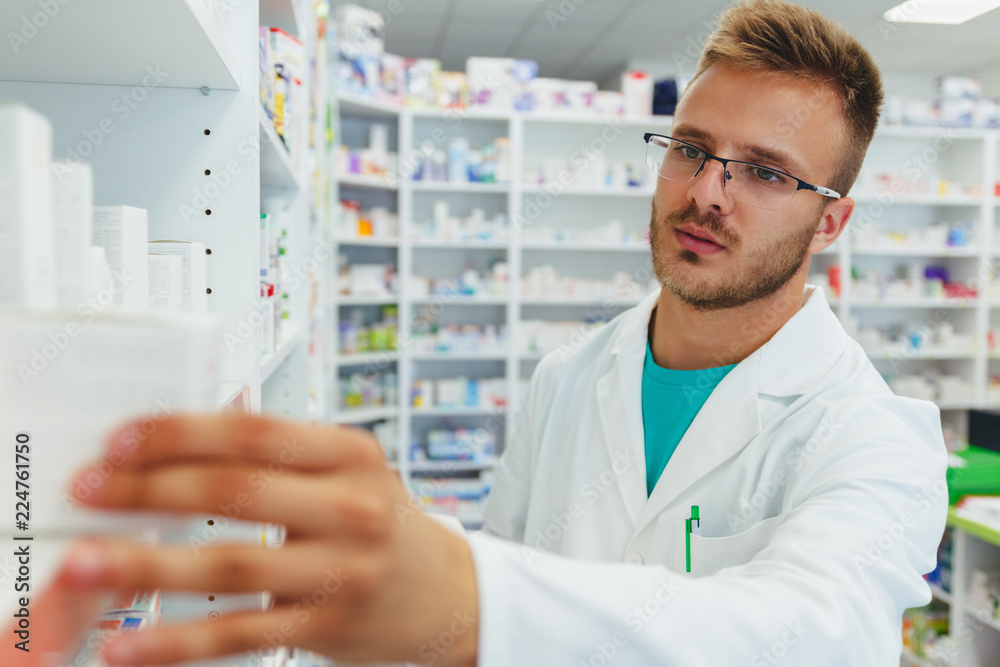 Serious pharmacists reaching for a medications among shelves at pharmacy drugstore