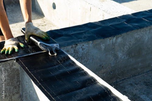 Workers carry out waterproofing of the Foundation for the construction of a wooden house.
