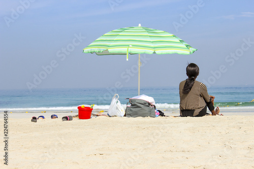 Fotografía childminder on the beach looking after child