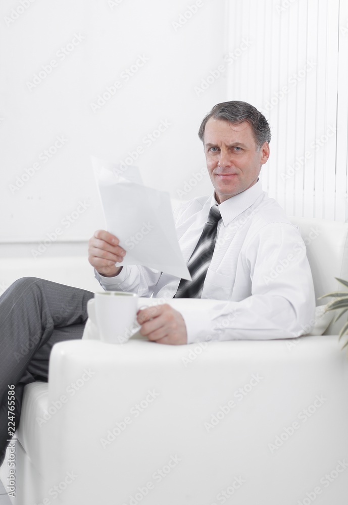 closeup. businessman reading a document while sitting in a chair in the hotel room. closeup. businessman reading a document while sitting in a chair in the hotel room.