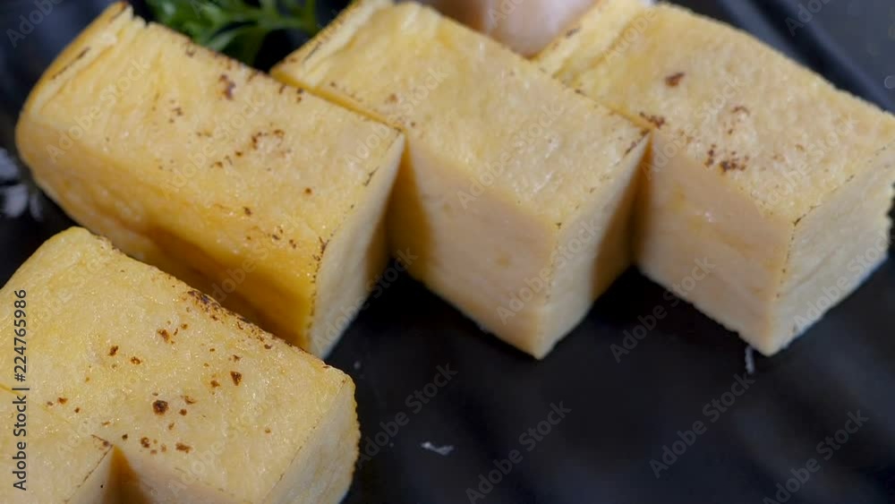 Motion video of Japanese Tamagoyaki, Japanese Omelette, sweet egg on black dish in the restaurant
