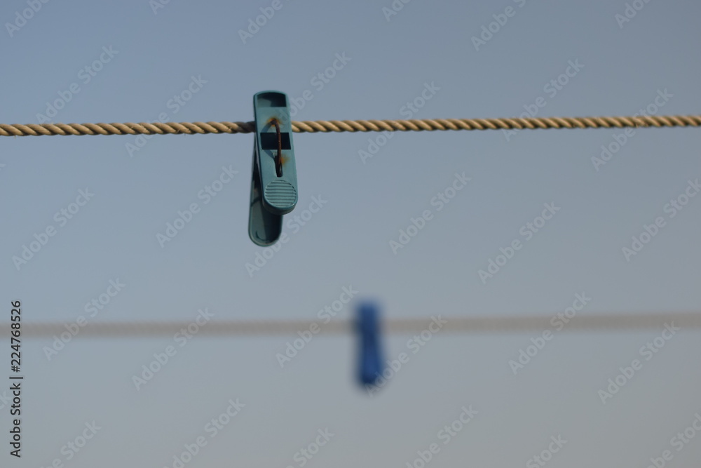 colorful clothespin hanging on a rope with blue sky in background colorful clothespin hanging on a rope with blue sky in background