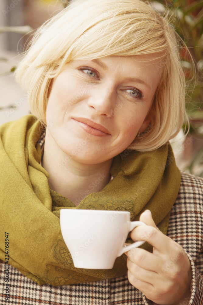 A beautiful young woman enjoying a cup of coffee near an old vintage window. A beautiful young woman enjoying a cup of coffee near an old vintage window.