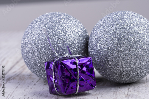 Bilde på lerret lila Geschenk mit silbernen Christbaumkugeln auf weißem rustikalen Holz hintergr