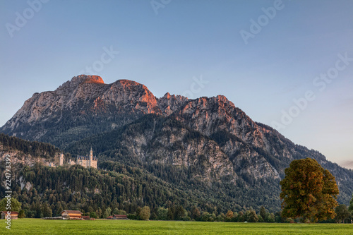 Schloss Neuschwanstein bei Sonnenuntergang mit Alpenglühen auf dem Berg Säuling im Hintergrund