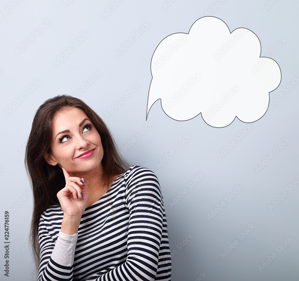 Beautiful young smiling business woman thinking and looking up on balloon cloud above on blue background