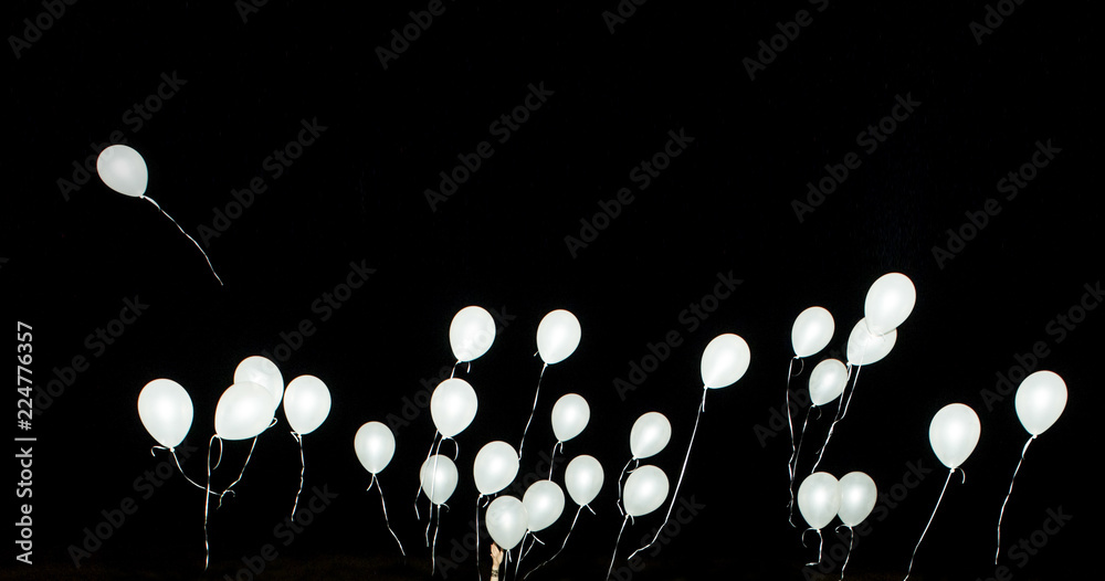 Fototapeta premium White Balloons and hand isolated on black background