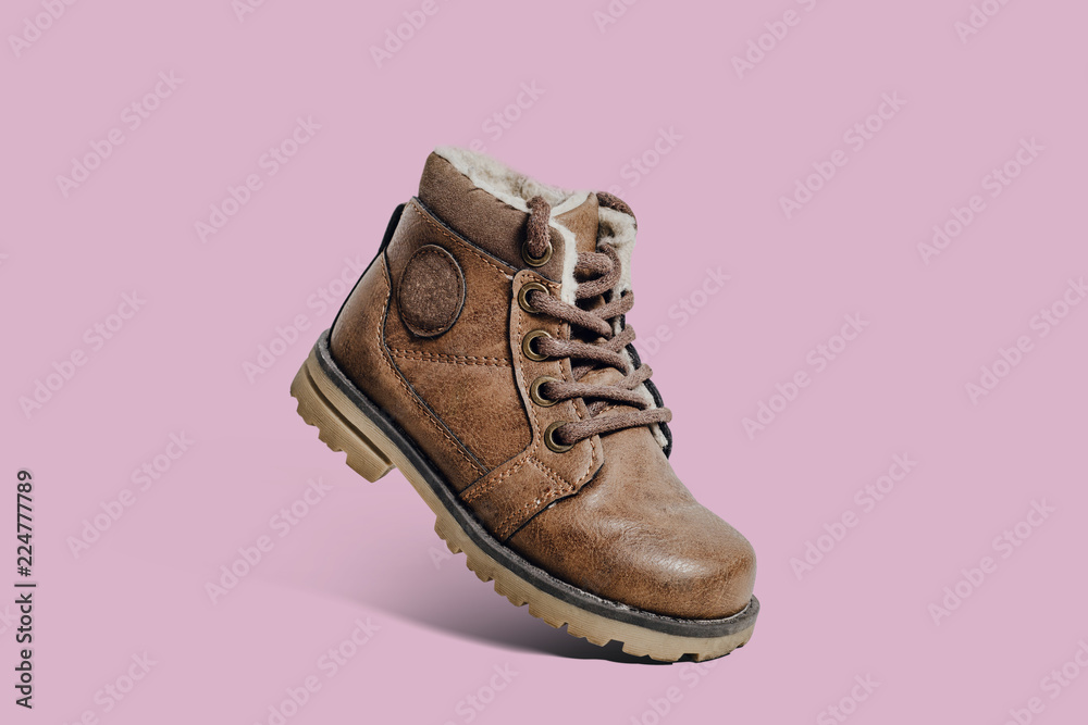 Leather, children's shoe on a pastel, pink background. The concept of upcoming cold, selling shoes. Warm, comfortable shoe for children with fur at an angle and inclination. Leather, children's shoe on a pastel, pink background. The concept of upcoming cold, selling shoes. Warm, comfortable shoe for children with fur at an angle and inclination.