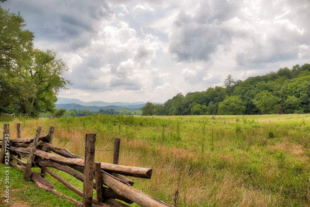 Green meadow with a brown wooden fence in the Great Smoky Mountains on a cloudy day