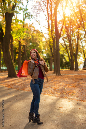 Beautiful young woman happy after shopping and walking in a park in autumn © Marko