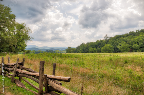 Green meadow with a brown wooden fence in the Great Smoky Mountains on a cloudy day
