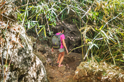 Young woman with hiking bag on a trekking trail in tropical rain forest