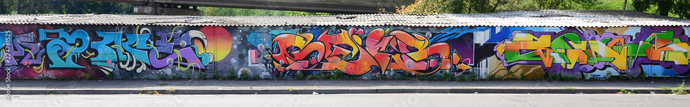 Obraz premium Fragment of graffiti drawings. The old wall decorated with paint stains in the style of street art culture. Multicolored background texture