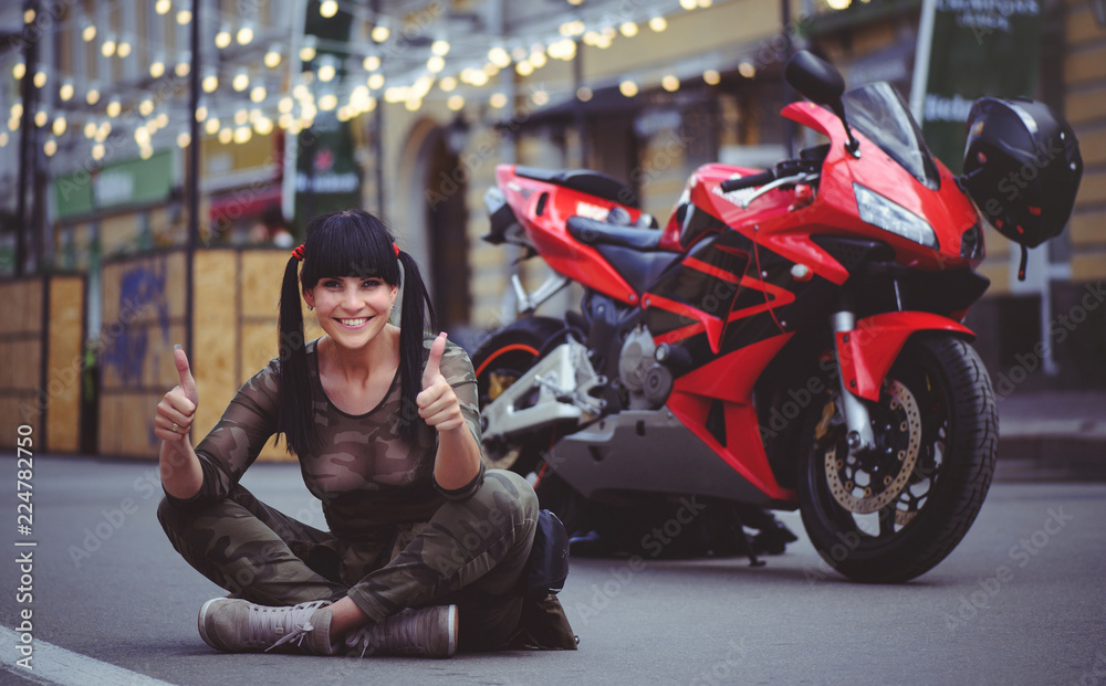 happy woman biker sitting near motorcycle and happy, close-up brunette with red bike