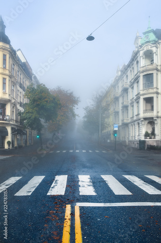 A magical, beautiful morning. Antique, old buildings. The road goes into the fog. Quiet city foggy morning. Autumn cold morning in a city street. Cloudy day. Oslo, Norway