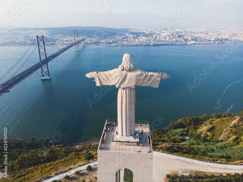 View of The Sanctuary of Christ the King, Cristo Rei, Almada, Lisbon, with 25 de Abril Bridge suspension Bridge, Tagus river, aerial drone view in summer sunny day photo