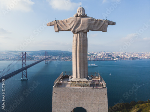 View of The Sanctuary of Christ the King, Cristo Rei, Almada, Lisbon, with 25 de Abril Bridge suspension Bridge, Tagus river, aerial drone view in summer sunny day photo