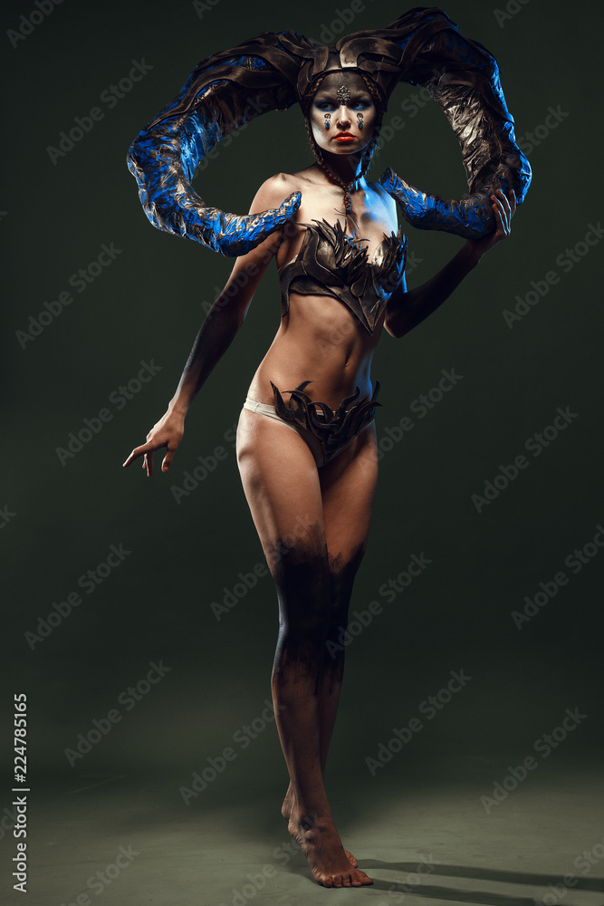 Beautiful and emotional girl on a dark background in the studio with a terrible makeup for Halloween Beautiful and emotional girl on a dark background in the studio with a terrible makeup for Halloween