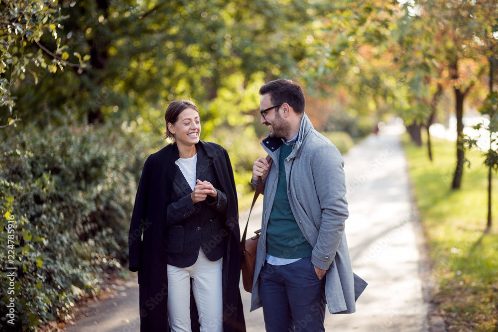 Businessman and businesswoman walking in a park and discussing Businessman and businesswoman walking in a park and discussing