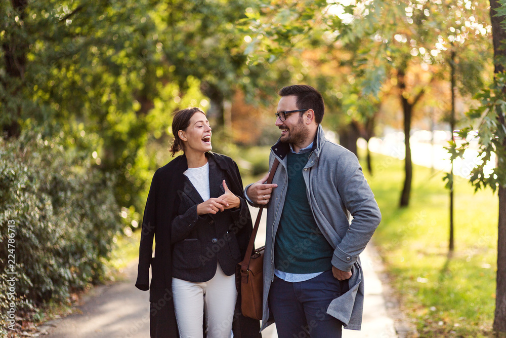 Businessman and businesswoman walking in a park and discussing Businessman and businesswoman walking in a park and discussing