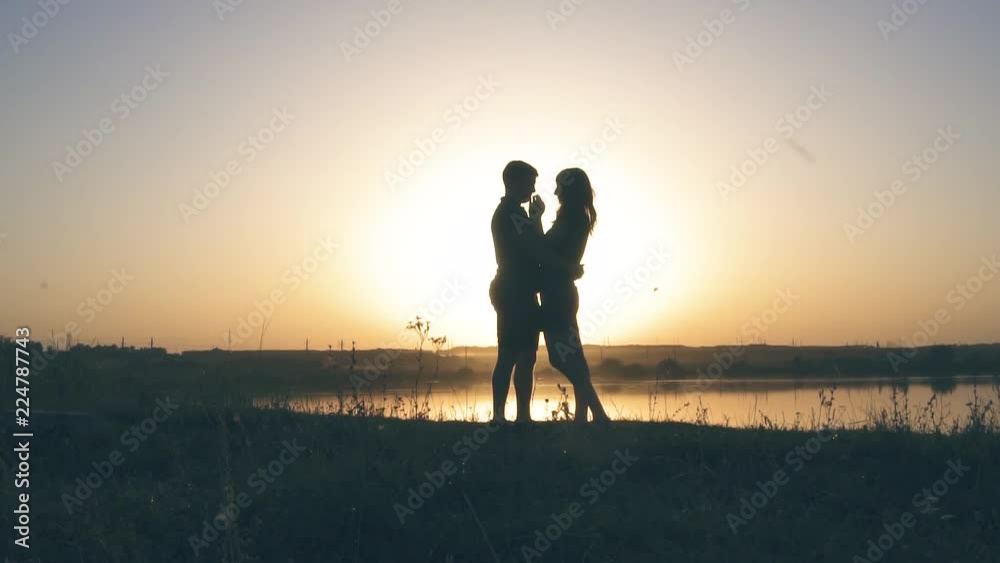 young enamored couple in nature in summer against the background of the river and sunset, there is noise on the video young enamored couple in nature in summer against the background of the river and sunset, there is noise on the video