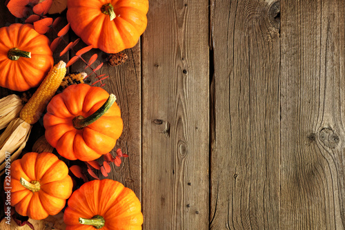 Autumn side border of pumpkins and fall decor on a rustic wood background with copy space