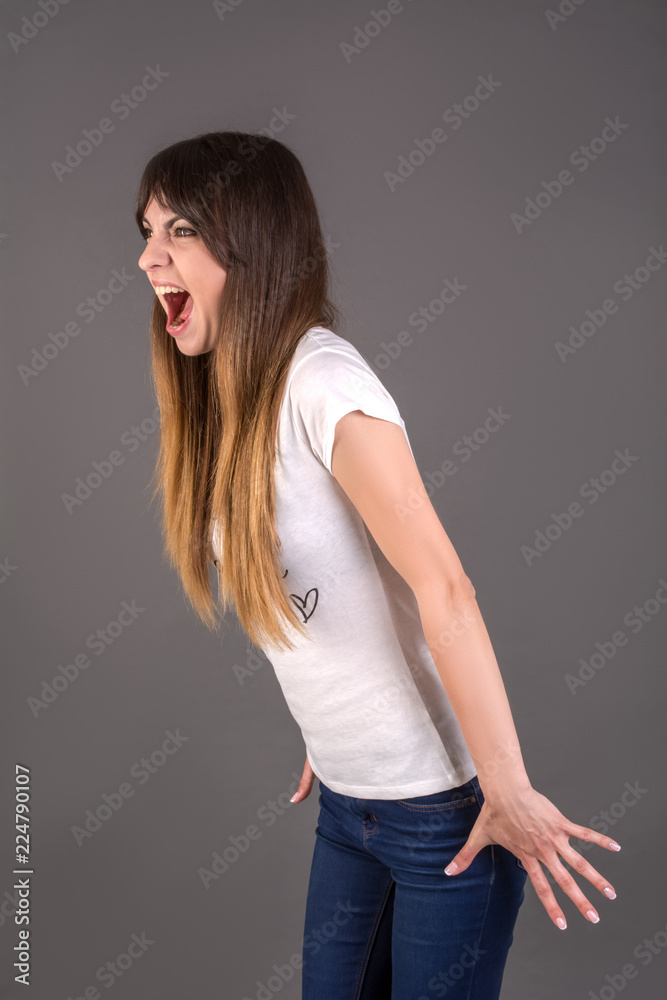 A young woman is shouting loudly. The girl screaming with wild open mouth. The concept about anger A young woman is shouting loudly. The girl screaming with wild open mouth. The concept about anger